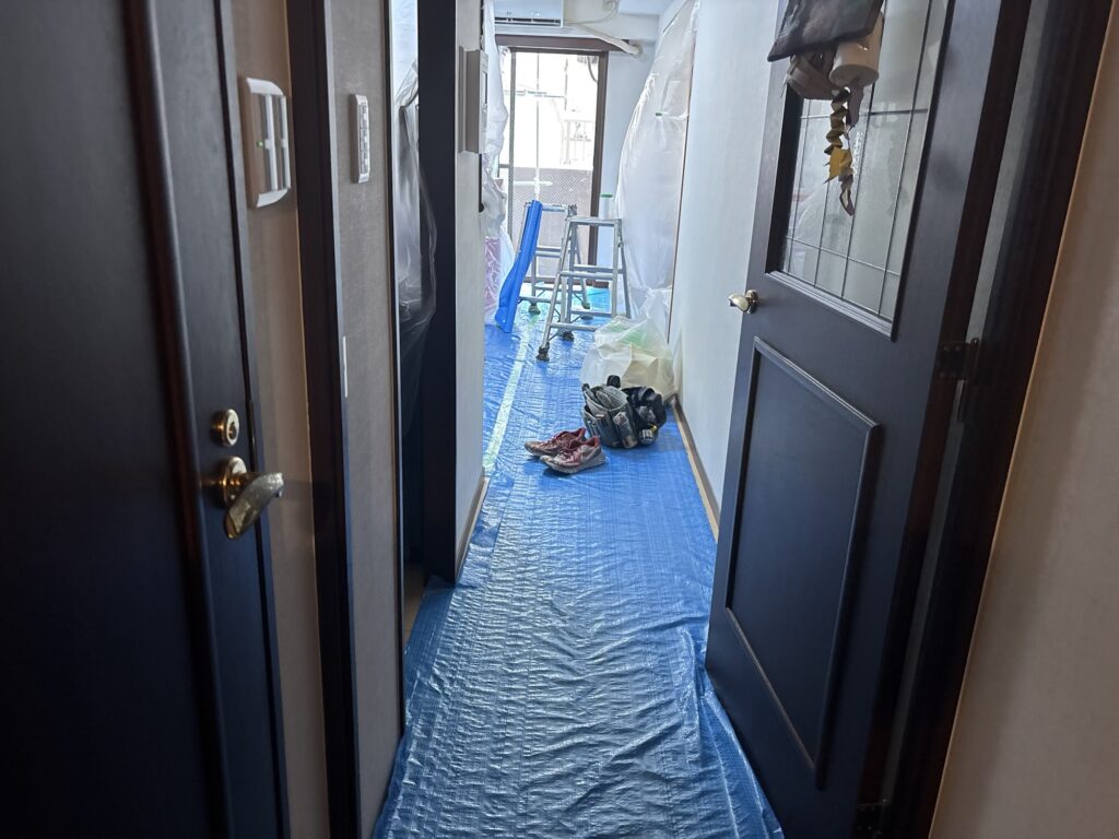 Protective floor covering installed in an occupied apartment before wallpaper replacement.