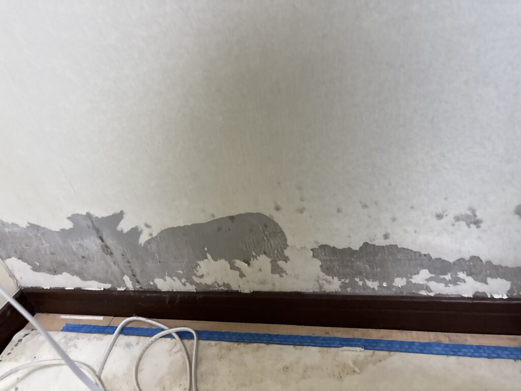 Removing old wallpaper from the walls of a Japanese condominium during renovation.