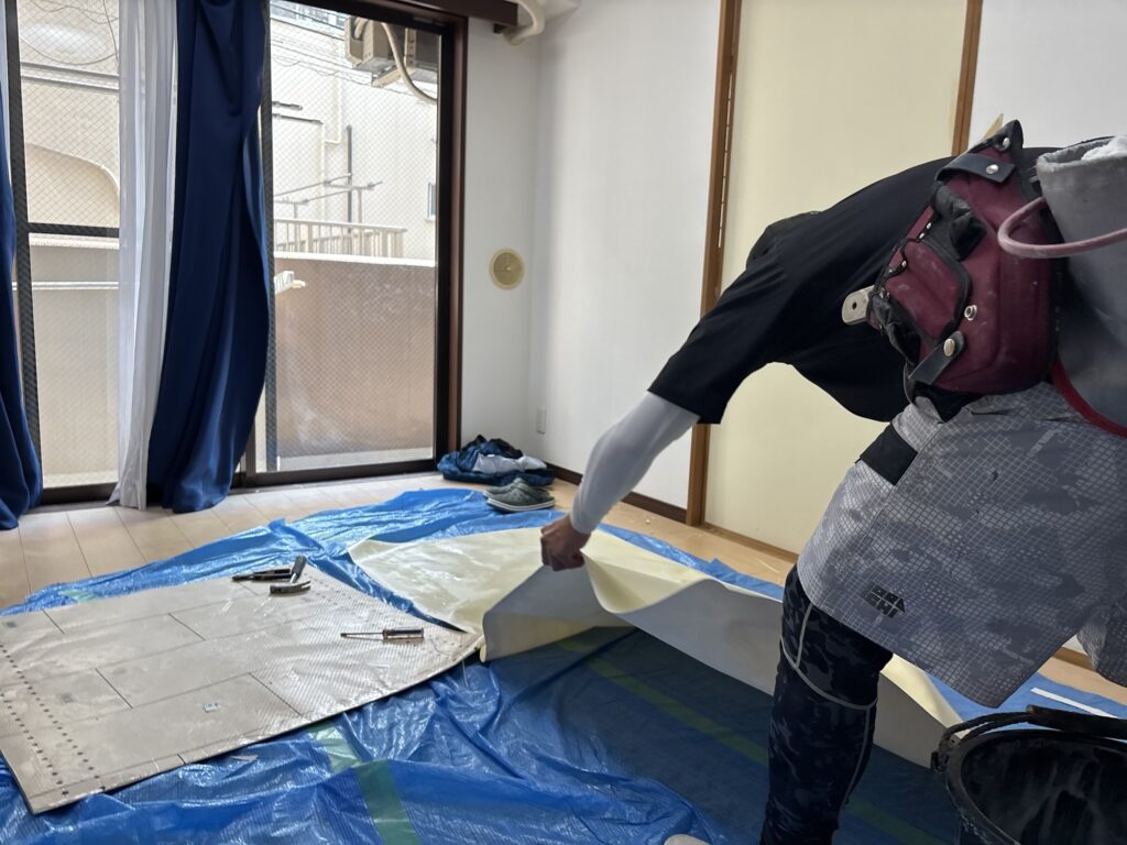 Wallpaper being prepared for a fusuma sliding door, with adhesive applied to the edges and the center lightly moistened with a damp sponge before installation.