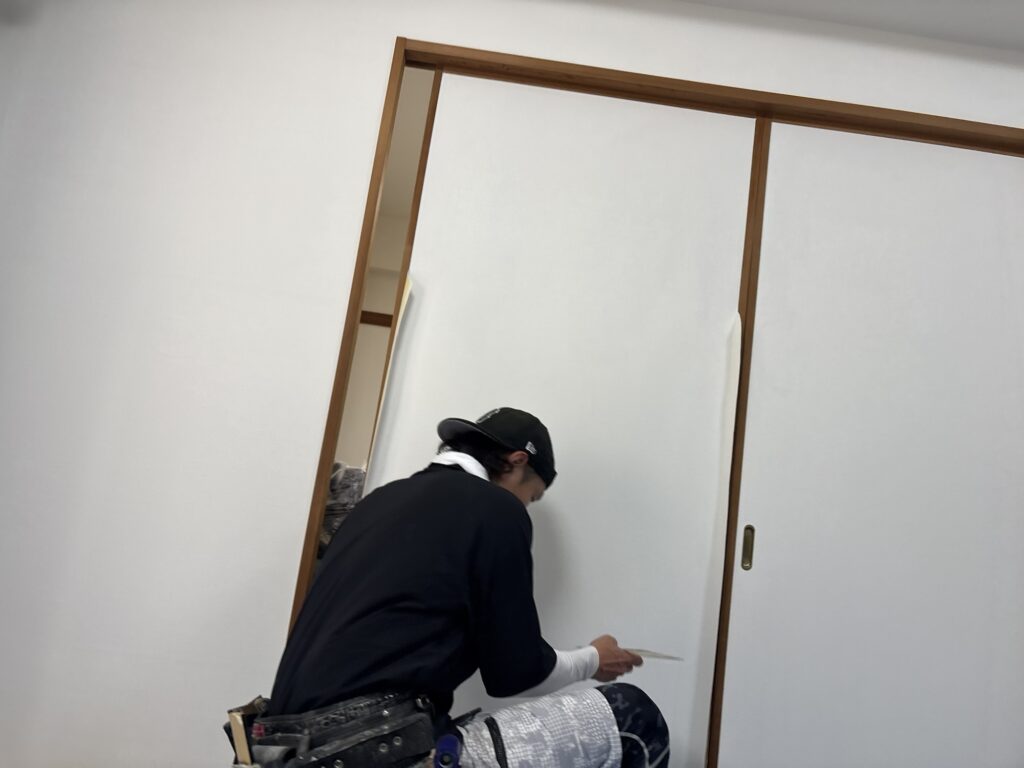 Installing wallpaper on a traditional Japanese fusuma sliding door using a specialized adhesive technique.