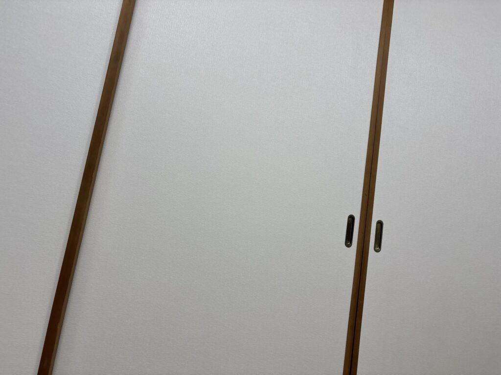 Freshly installed wallpaper on a traditional Japanese fusuma sliding door with neatly finished edges and a smooth, professional appearance after renovation.