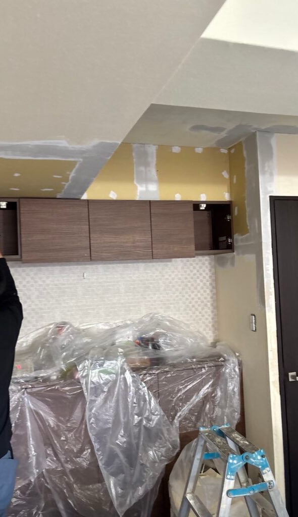 First coat of joint compound applied to a wall before wallpaper installation.