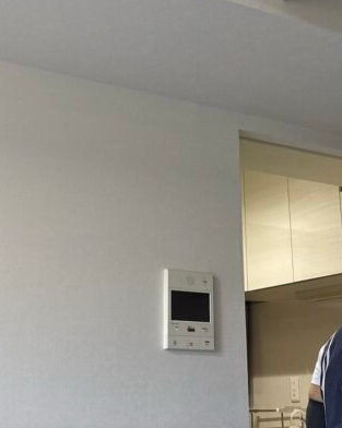 Wallpaper being installed around a fixed intercom with the joint positioned through the center.