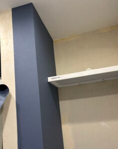 Worker smoothing navy blue wallpaper with a wallpaper smoother to remove air bubbles during installation.