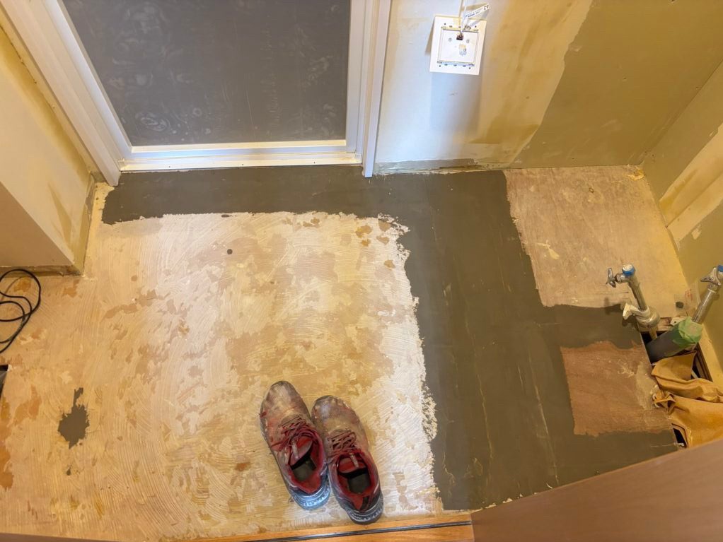 Floor filler applied before vinyl flooring installation in a bathroom vanity area.
