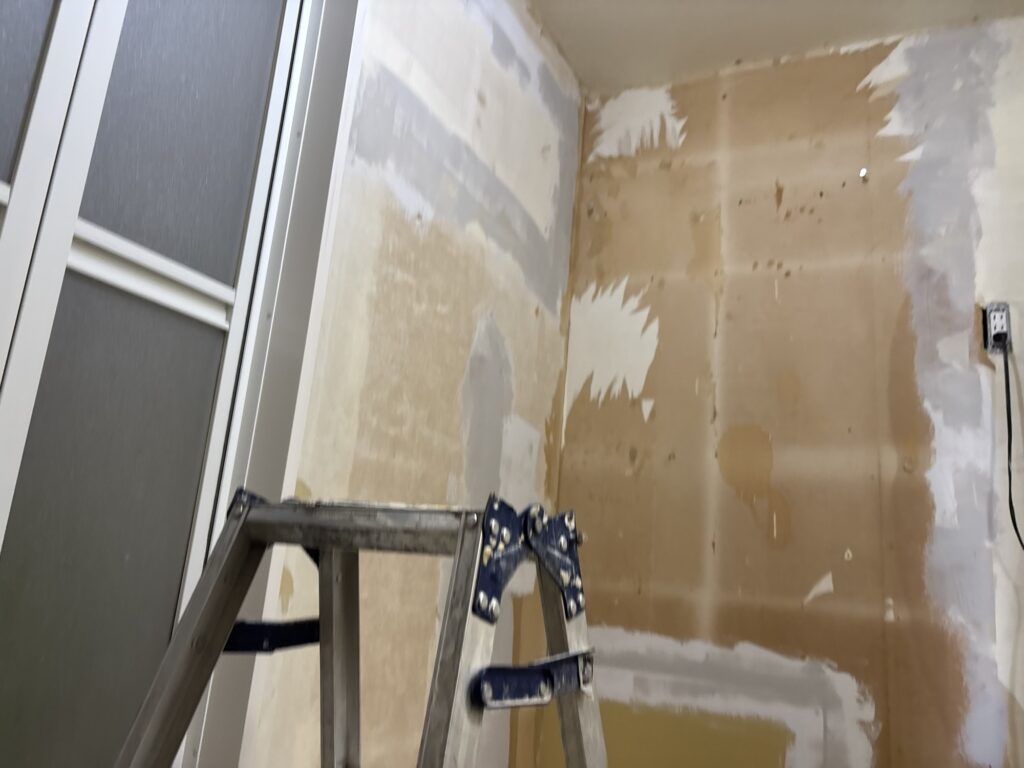 Base coat of joint compound applied to drywall before wallpaper installation.