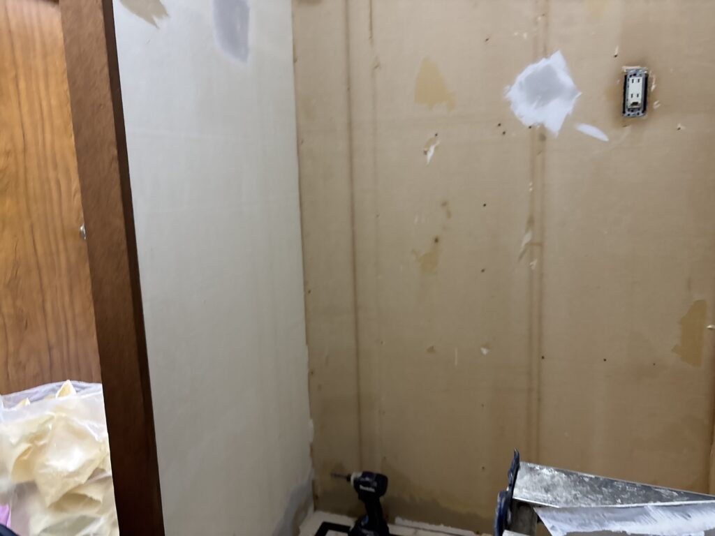 Laundry room with washing machine and storage fixtures removed before wallpaper installation.