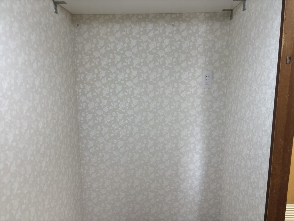Finished residential laundry room renovation featuring patterned wallpaper, new vinyl flooring, and white baseboards.
