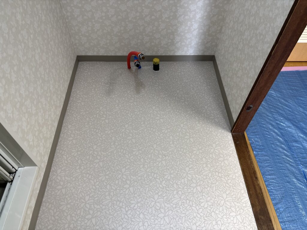 Completed vinyl flooring installation in a residential laundry room.