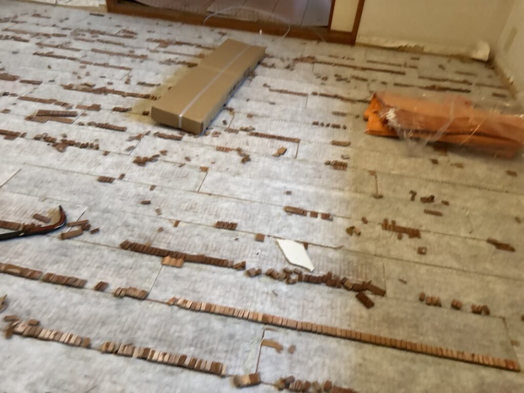 Wood remnants from old flooring stuck to the subfloor after flooring removal