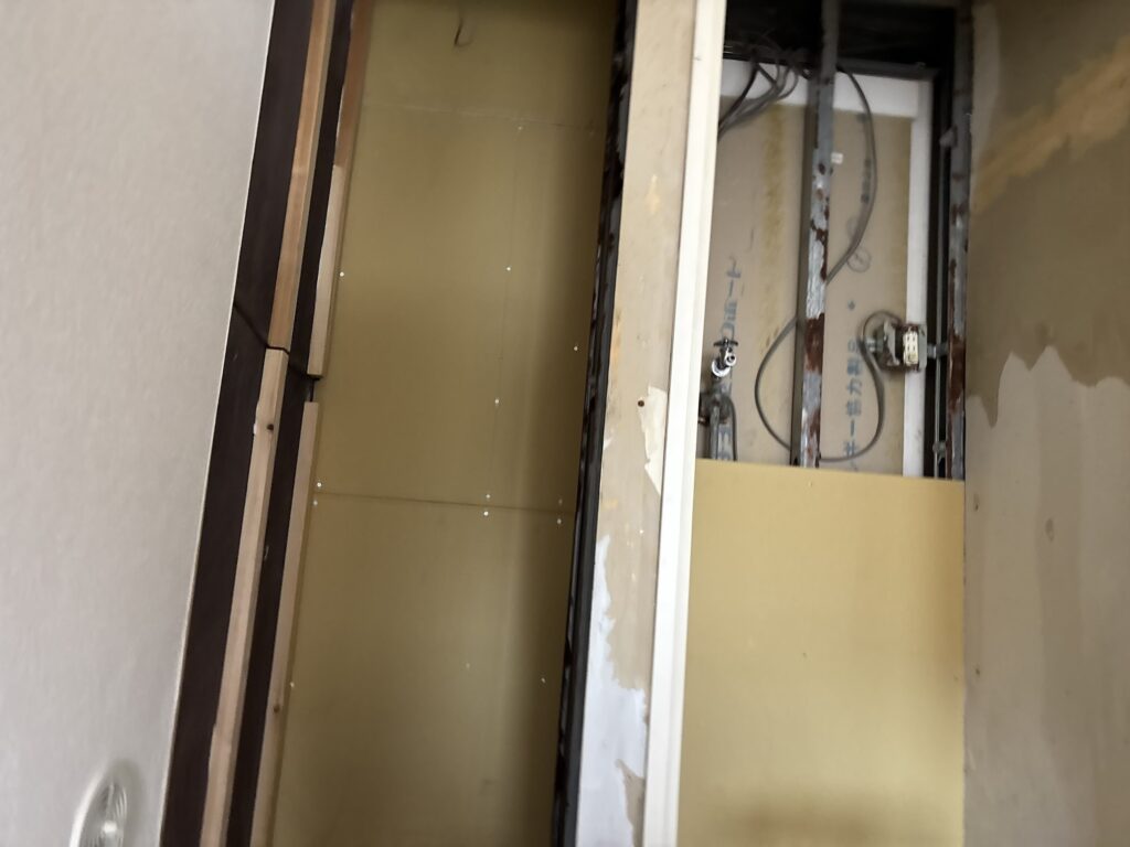 New drywall panels secured to light-gauge steel framing during a laundry room renovation.