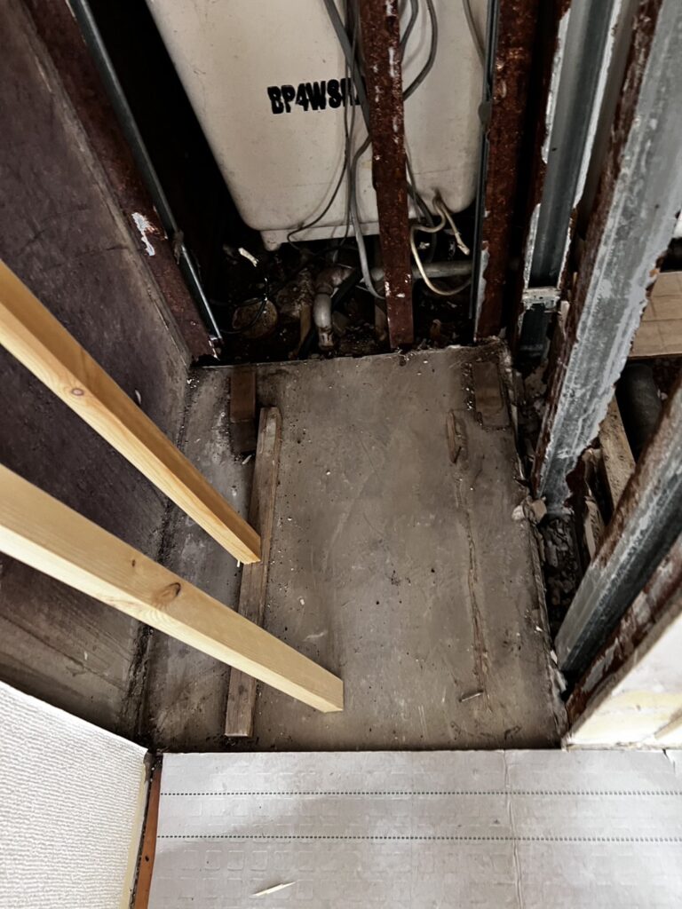 Storage shelf floor after demolition with the original framing exposed before reconstruction.