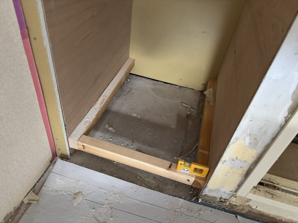 Photo of floor joists being assembled for a shelf, with wooden beams arranged in a grid pattern to form the subfloor structure.