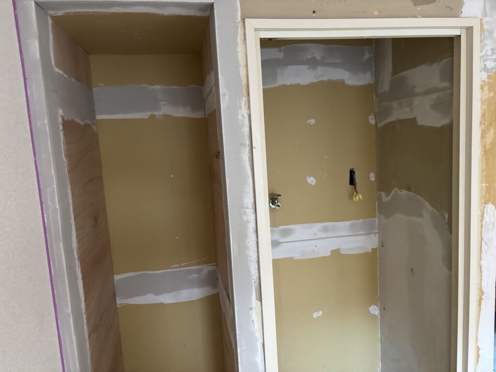 Photo of a wall or surface after 12mm gypsum board and 12mm plywood have been attached, with base putty applied over the joints and surface.