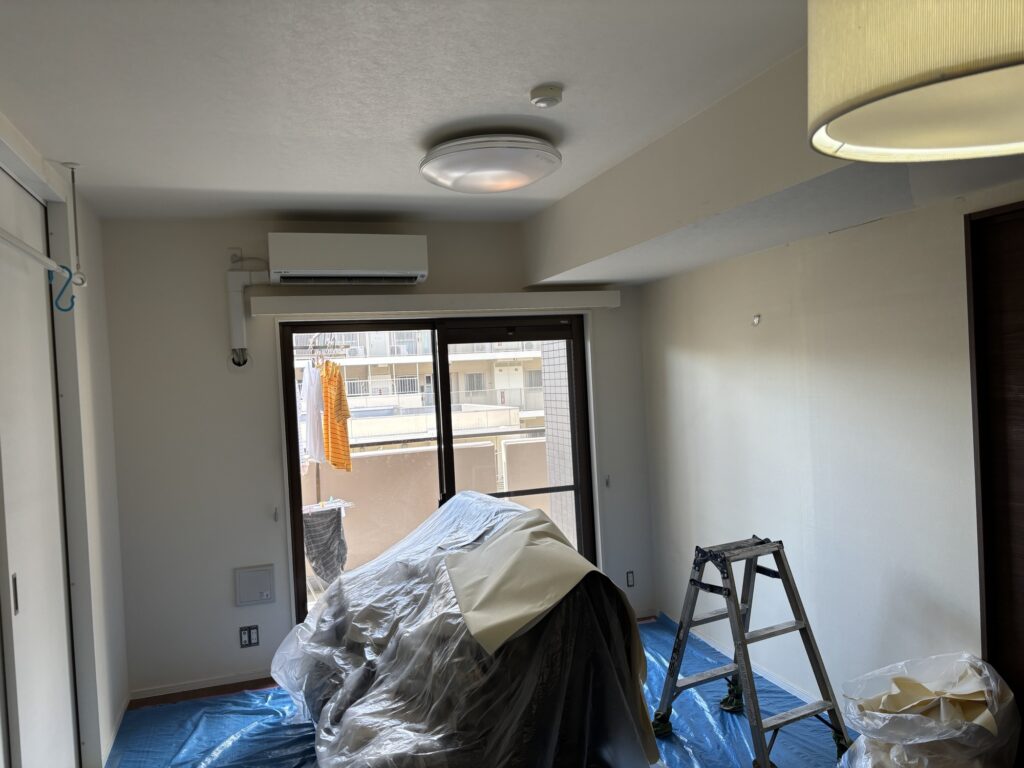Blue protective sheets covering the floor before wallpaper installation in a Japanese apartment.