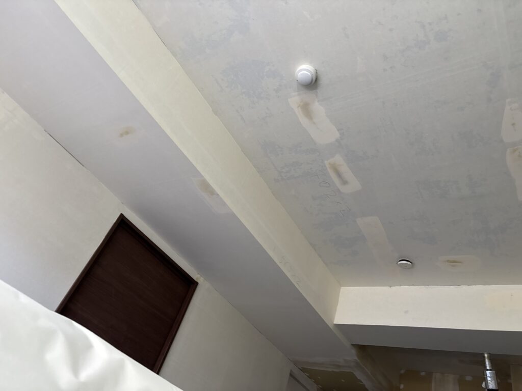 Ceiling with old wallpaper removed and finishing joint compound applied before new wallpaper installation.