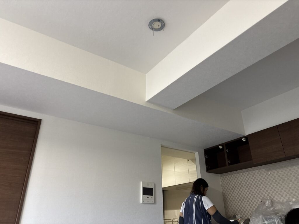Wallpaper being installed around a fixed intercom with the joint positioned through the center.