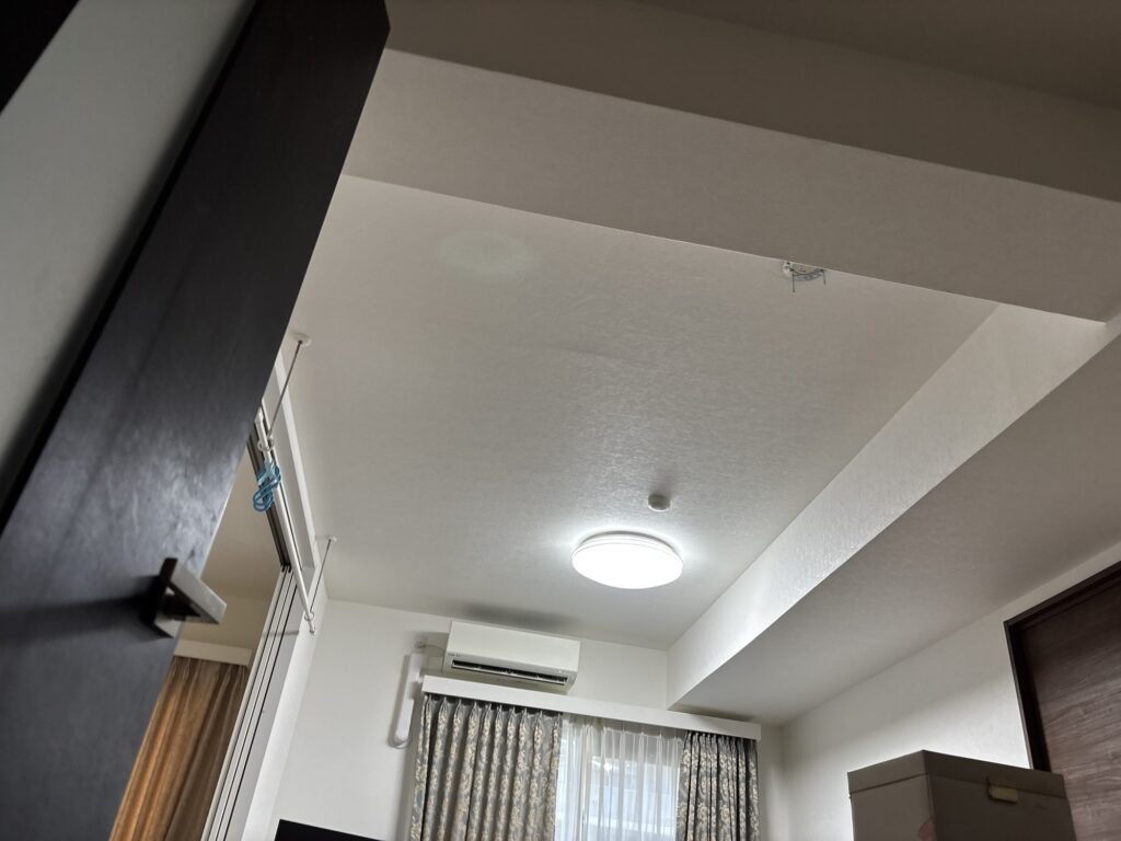 Long stone-textured wallpaper being installed on a 4.2-meter-long living room ceiling.