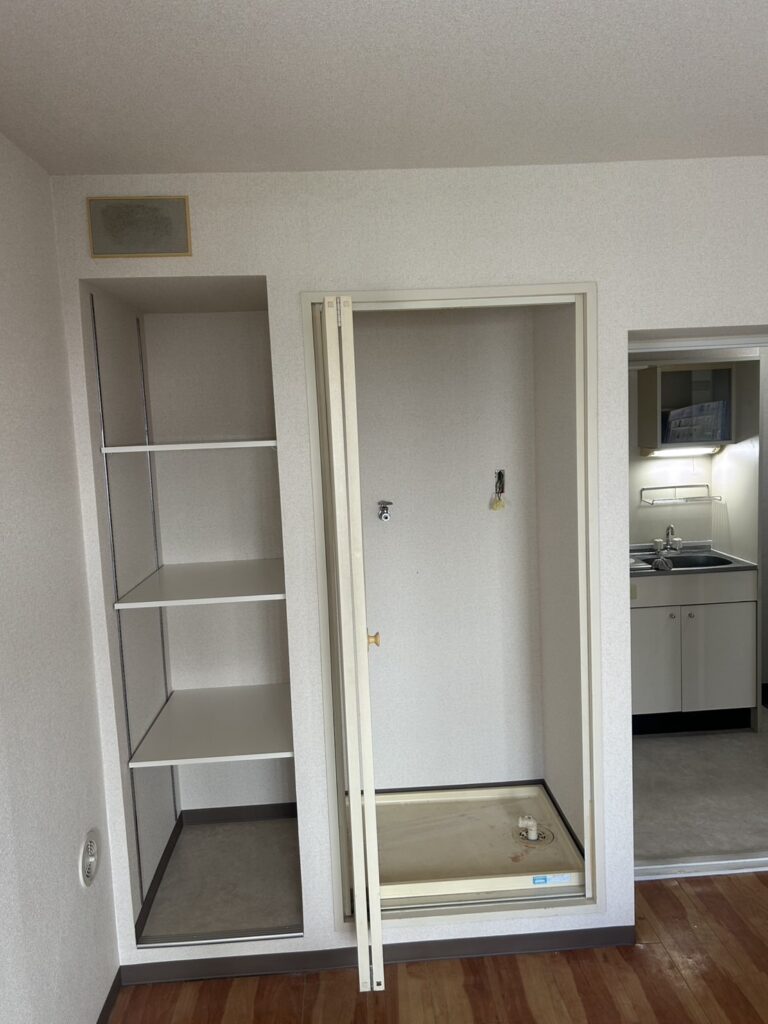 Completed laundry area and storage shelf with new wallpaper and cushion flooring after renovation.