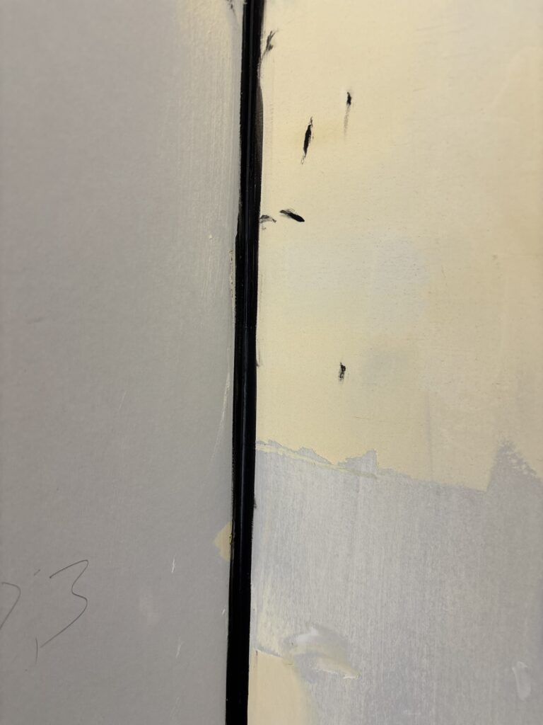 Black joint caulk applied to room corners before black wallpaper installation