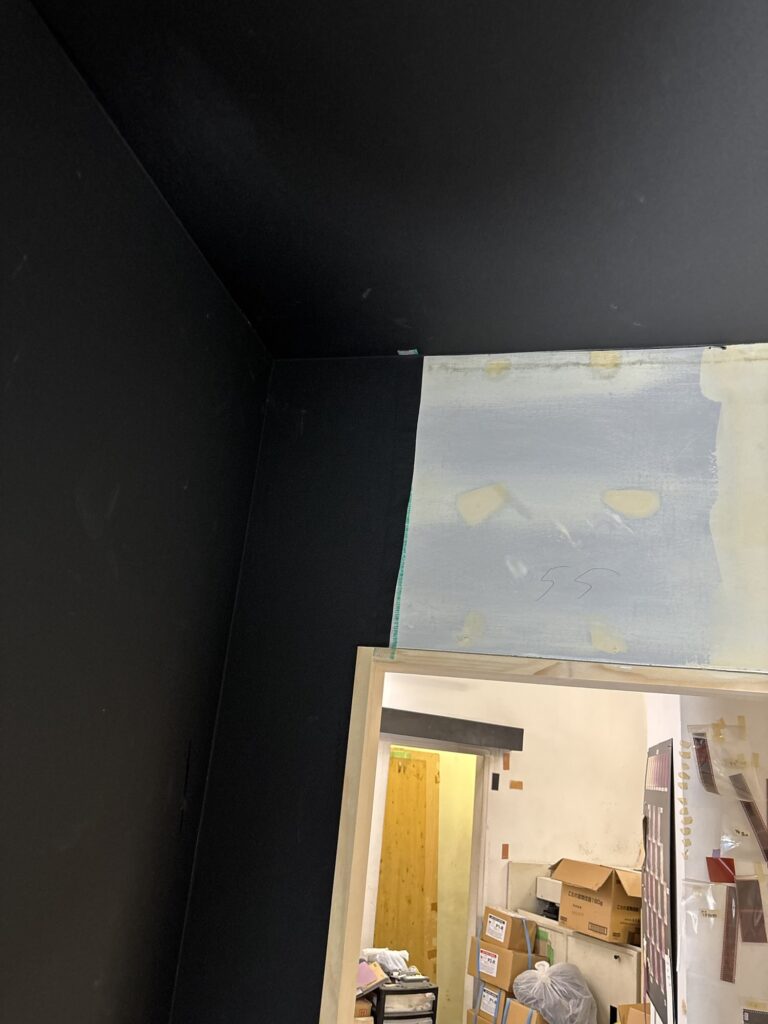 Thin black wallpaper being installed on a wall