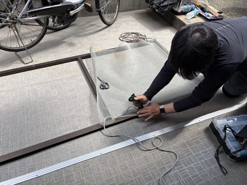 Using a screen roller to install rubber spline and secure new mesh in a Japanese screen door frame