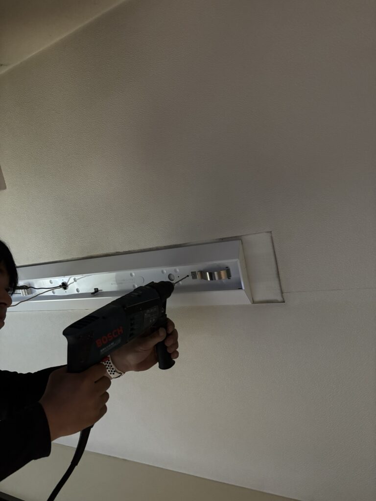 Using a rotary hammer drill to create new mounting holes in a concrete kitchen ceiling