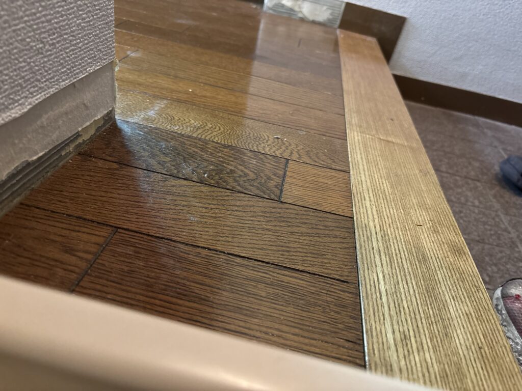 Existing wooden floor transition before height adjustment for vinyl flooring installation.