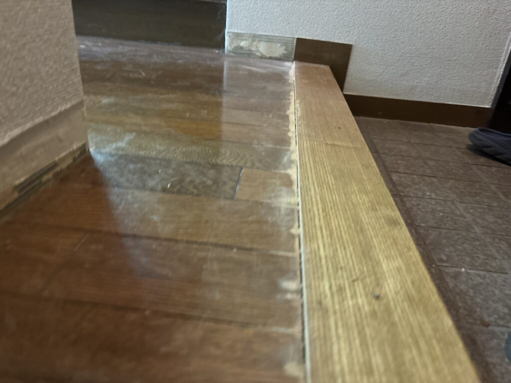 Existing floor transition being trimmed to create clearance for new vinyl flooring.