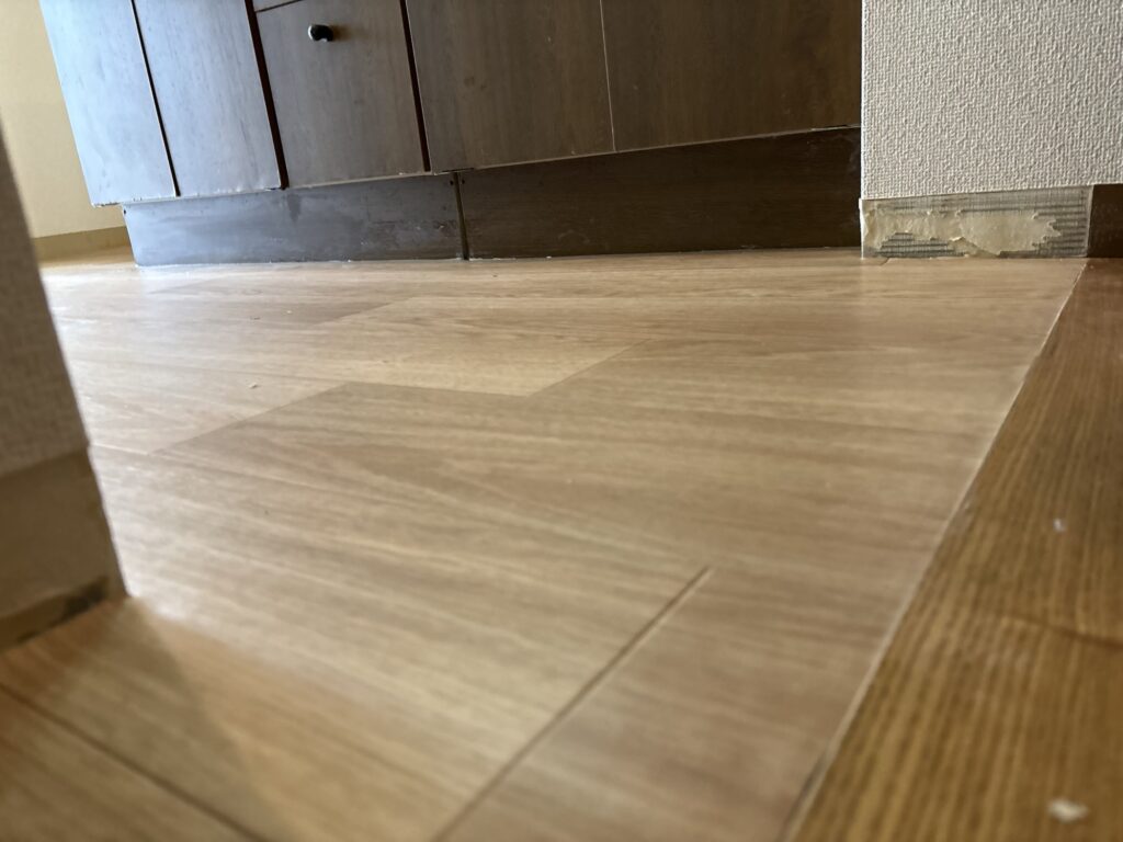 Newly installed vinyl flooring fitting below the existing transition without exceeding the transition height.