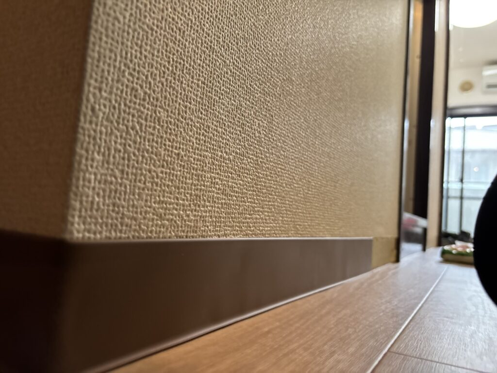 Soft vinyl baseboard being shaped around a corner during apartment renovation.