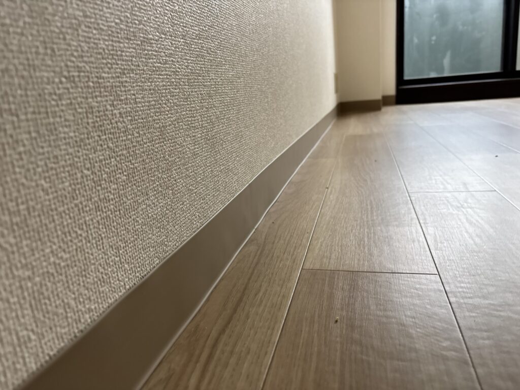 New soft vinyl baseboard installed along the wall above the newly installed vinyl flooring.