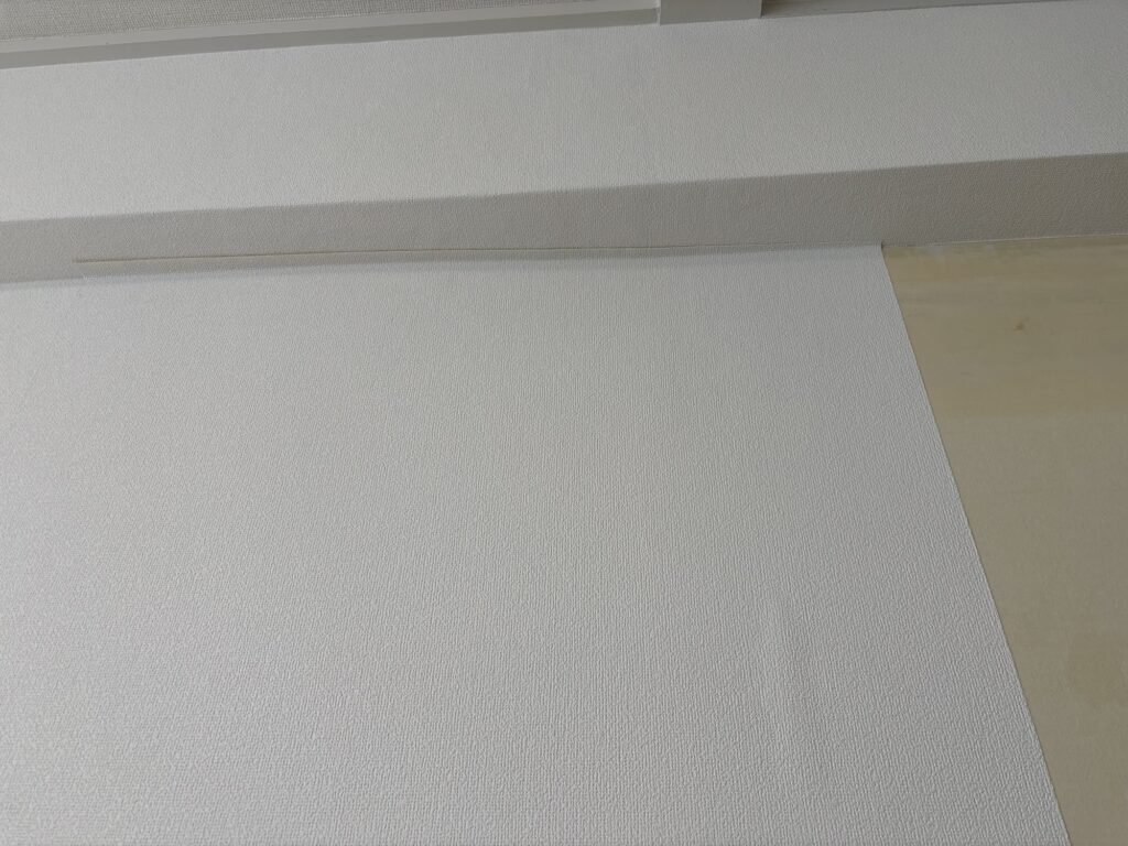 Small temporary bubble visible on newly installed wallpaper caused by moisture in the old backing paper.