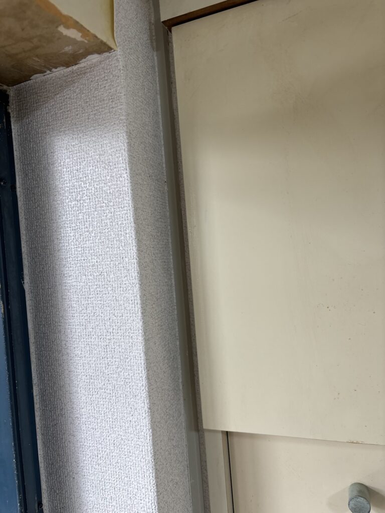 New wallpaper installed in a narrow space beside a kitchen door frame.