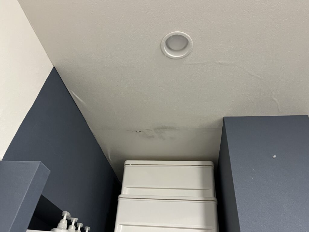 Water-damaged gypsum board ceiling with cracked areas and torn wallpaper in a Japanese apartment.