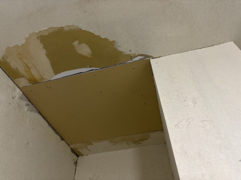 Close-up of newly installed gypsum board on the repaired section of a water-damaged ceiling.