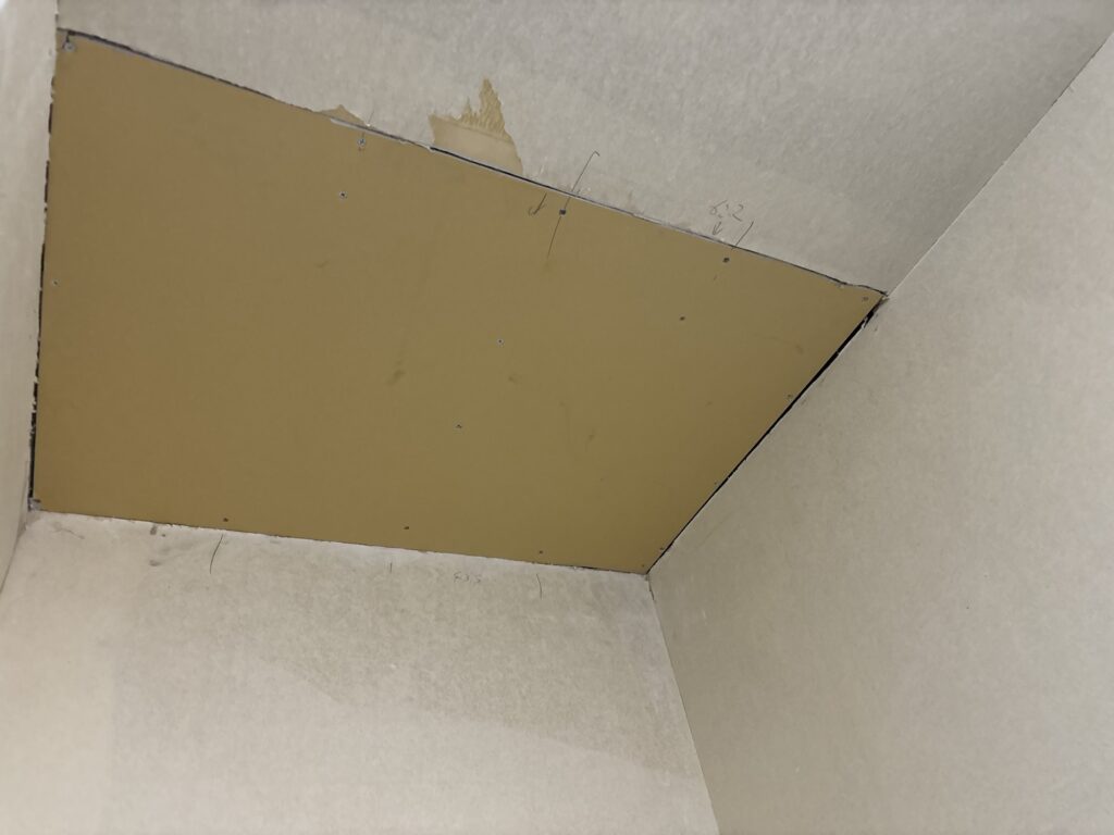 New gypsum board installed on a repaired section of a water-damaged apartment ceiling.
