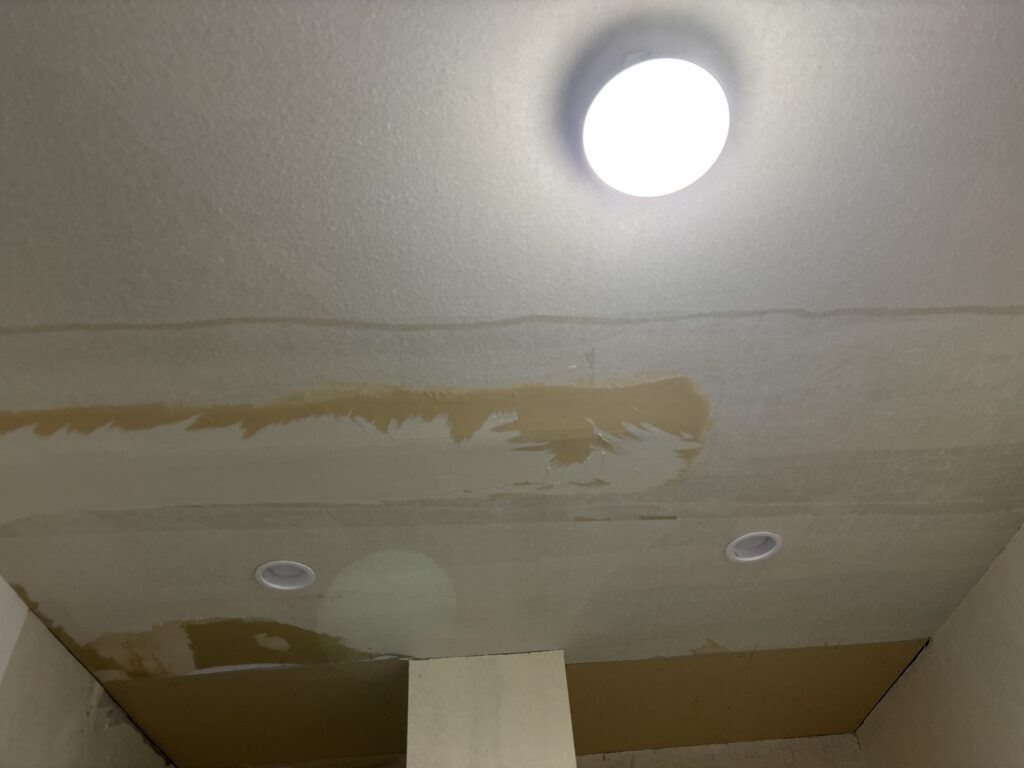 Ceiling after removing the damaged wallpaper and installing new gypsum board in the water-damaged area.