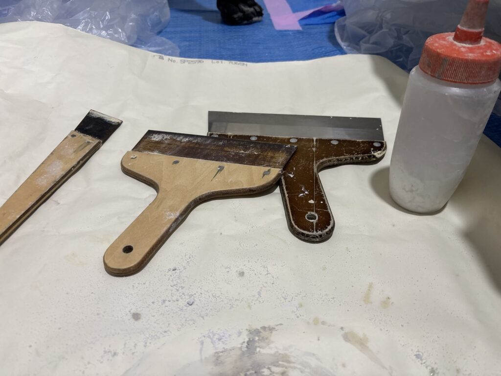 Small, medium, and large putty knives used for applying joint compound during ceiling repair.