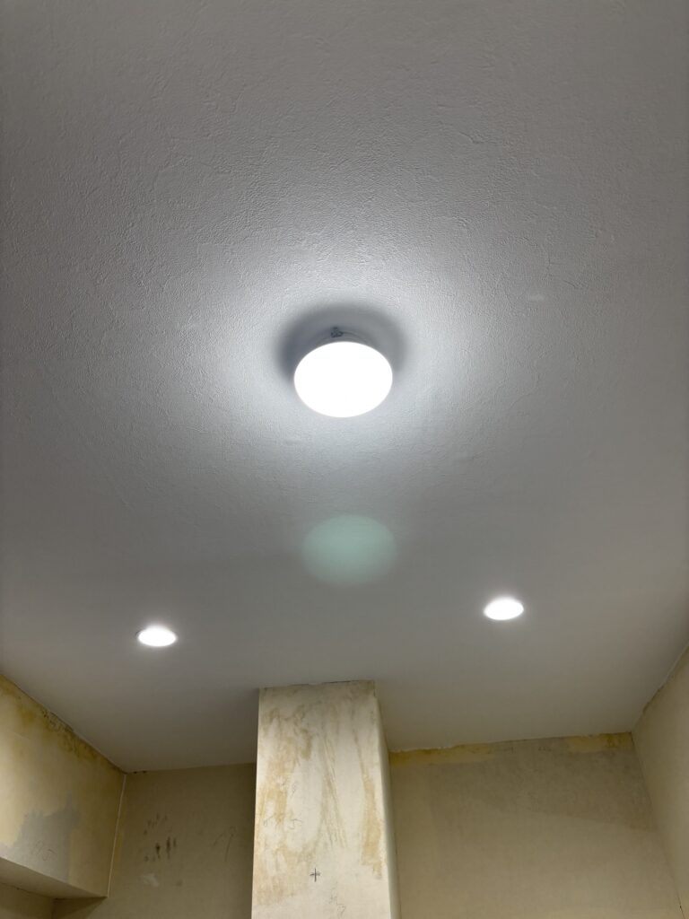 Completed white stone-pattern wallpaper installation on a repaired apartment ceiling.