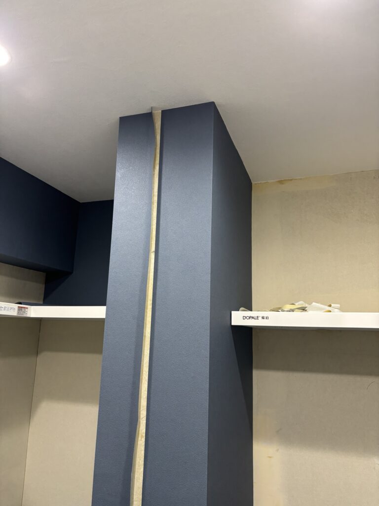 Navy blue wallpaper being installed on an apartment wall during a renovation project.