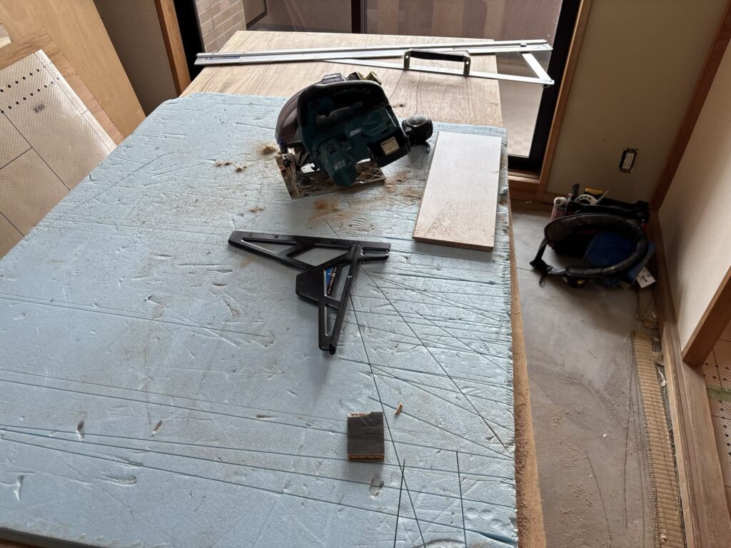 Worker cutting a flooring board with a power circular saw during apartment renovation.