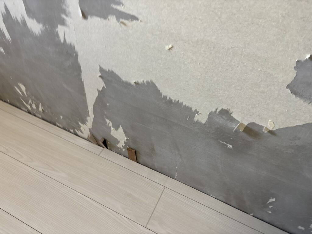 Wedges securing the edge of newly installed wood flooring while the adhesive cures.