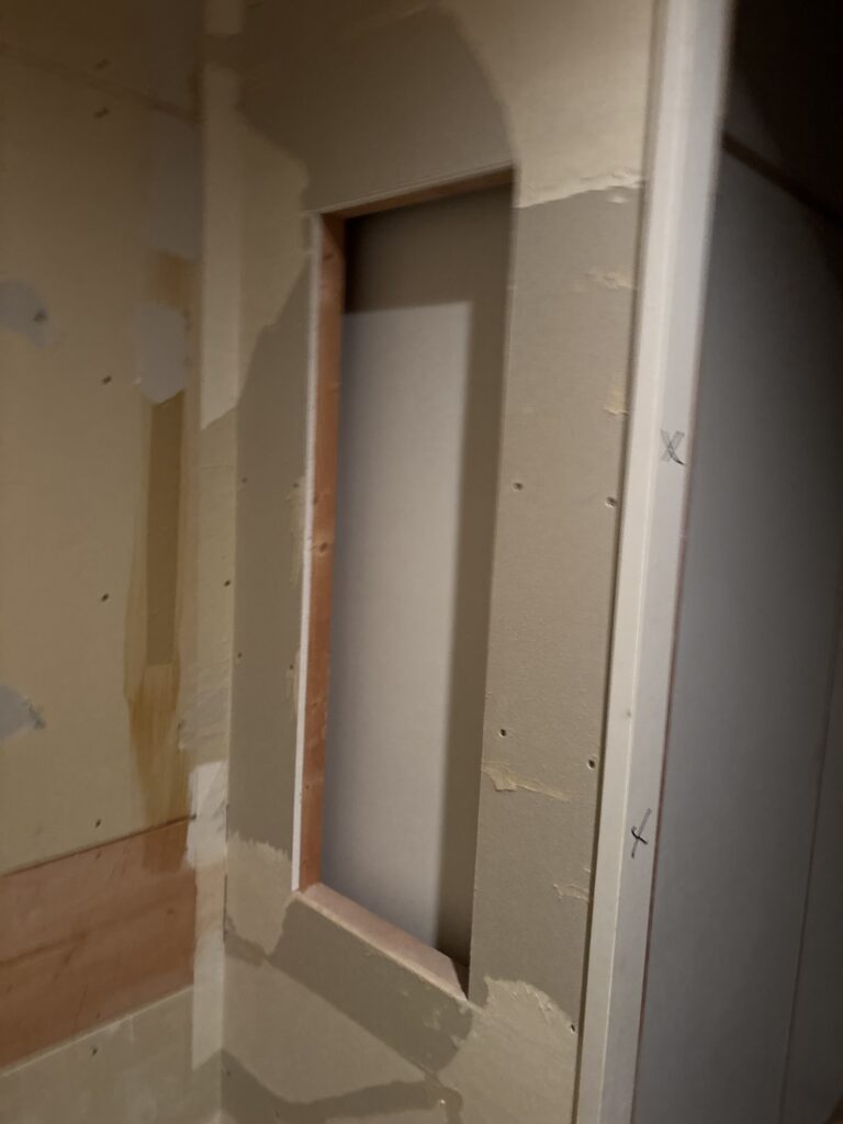 Opening left after removing an old storage shelf in the changing area near the bathroom.