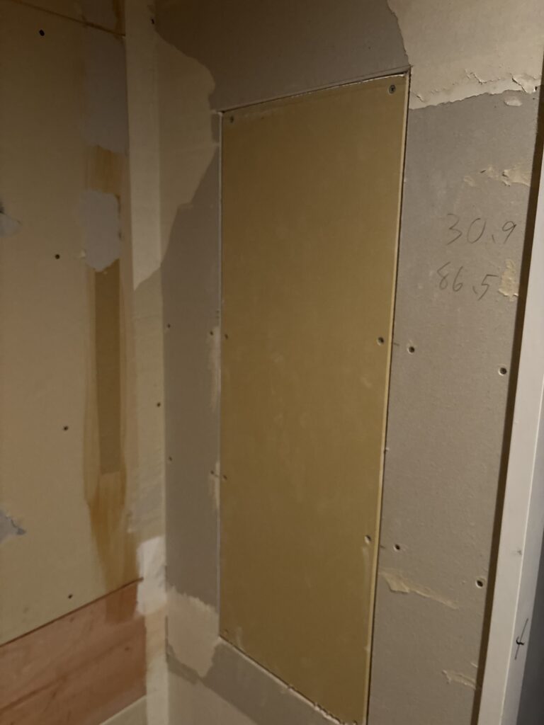 New drywall installed in the opening after removing a storage shelf.