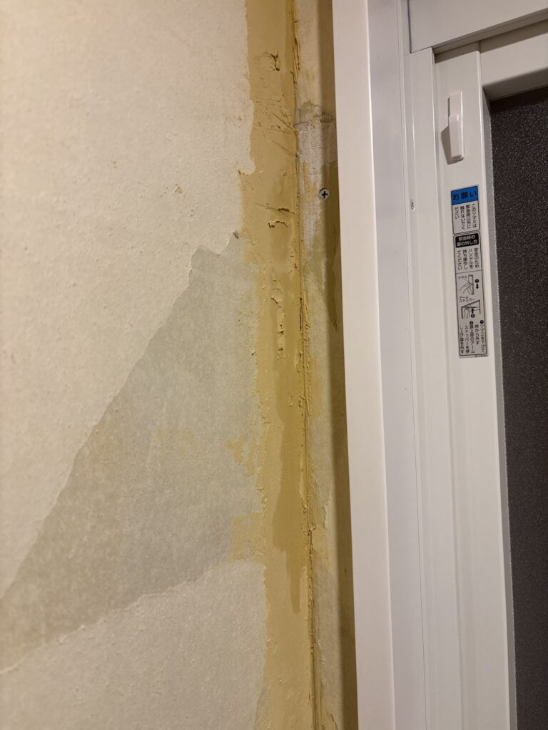 Uneven wall filler surface before sanding and wallpaper installation.