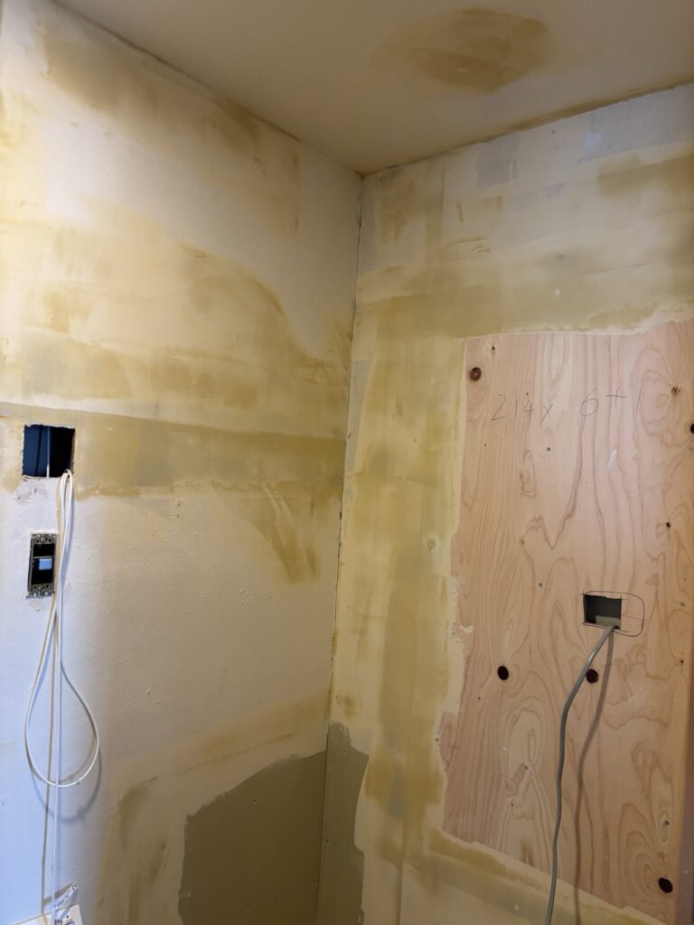 Finishing filler applied to bathroom walls and ceiling before new wallpaper installation.