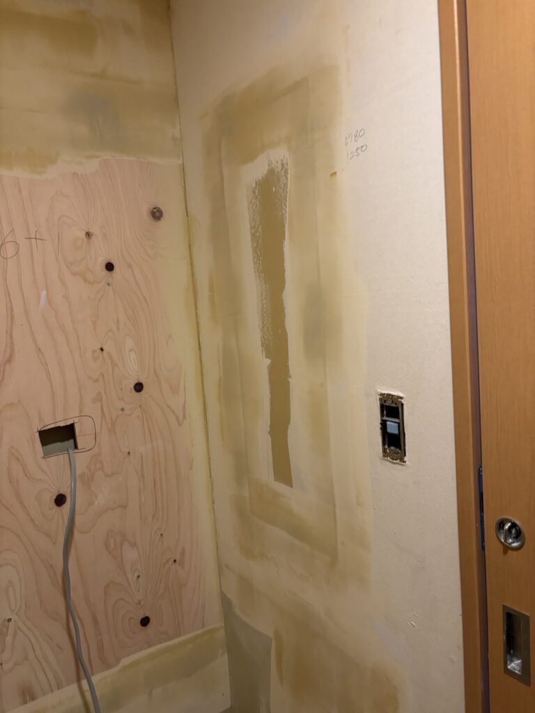 Finishing filler applied to a bathroom wall before wallpaper installation.