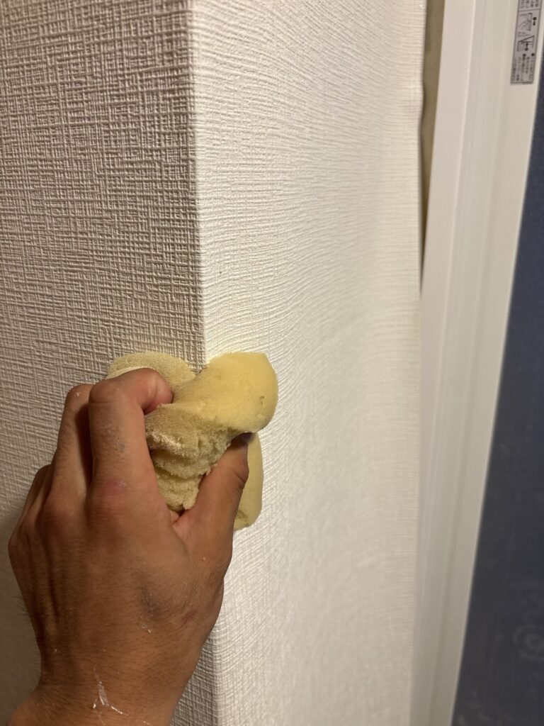 Wallpaper being wrapped around an outside corner of a bathroom wall.