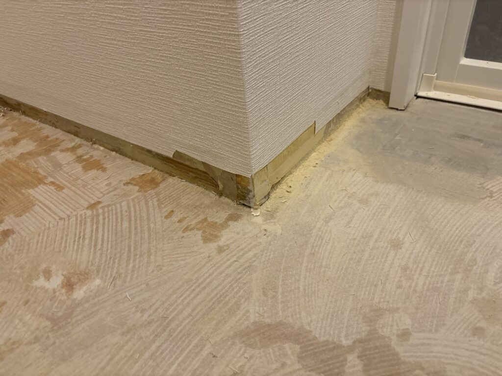 Wallpaper trimmed below the 6 cm soft baseboard height at an outside corner to prevent wrinkles in the freshly installed wallpaper.